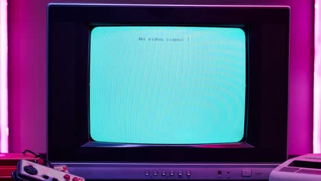 old television with blue screen on pink neon background. close-up of vintage tv and cartridges for retro playstation. antique video game, nostalgia