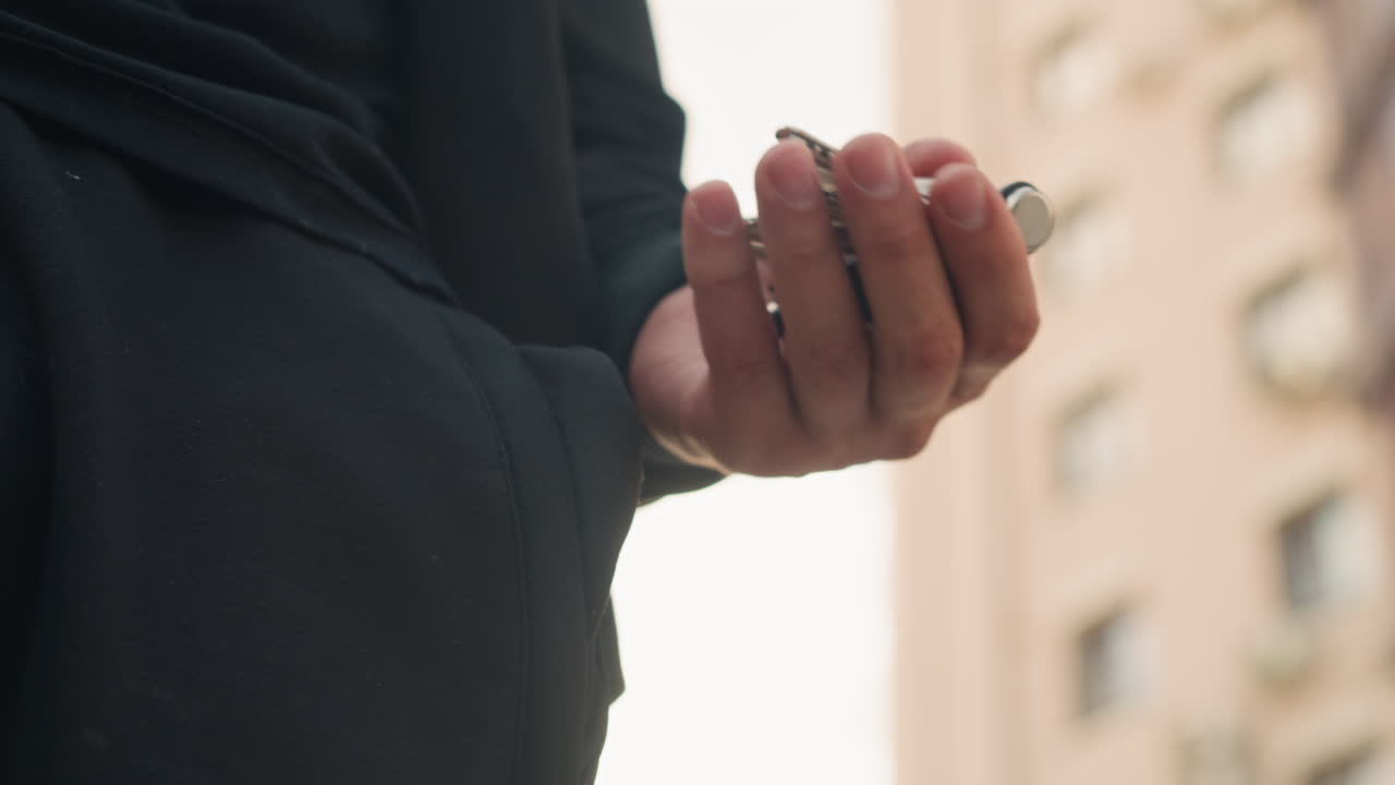 도시 풍경 배경이 차분한 분위기를 더하고, 어두운 옷을 입은 사람이 아늑한 주거지에 도착하는 모습이에요. 라운지 복장을 한 개인이 도시 아파트에 다가가는 차분한 도시의 저녁 풍경입니다.