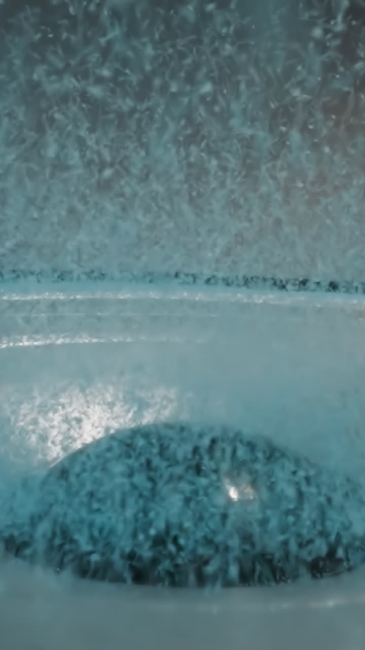 Blue sand for aquarium lies on edge of loudspeaker diaphragm and flows from movement to dust cap in center. Small granules moves on electrodynamic speaker driver macro