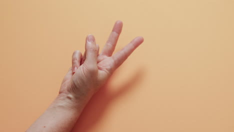 cerca de la mano de una mujer cacauana que muestra un signo de paz con espacio de copia en un fondo amarillo