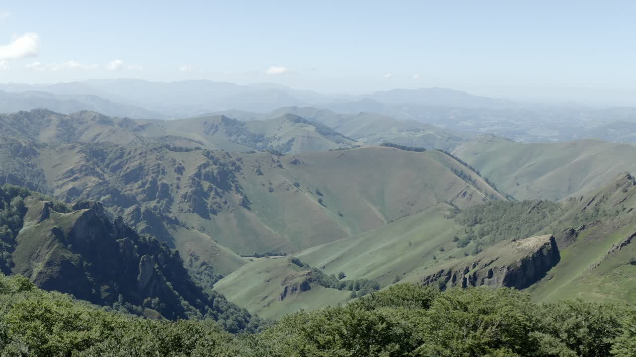 Aerial view over grassy foreground revealing vast mountain range under hazy sky, Col de Sourzay, Lecumberry, France