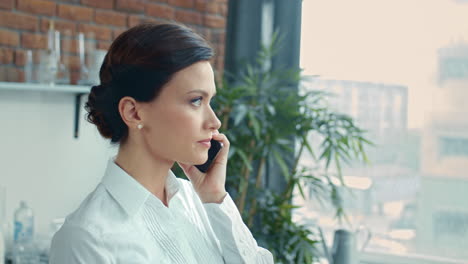 Businesswoman-speaking-cell-phone.-Woman-looking-on-daily-planner-in-kitchen.