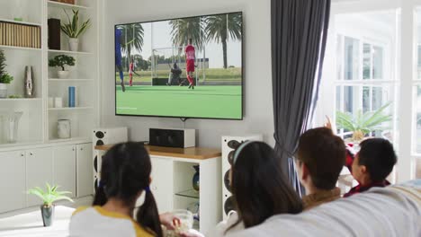 Compuesto-De-Familia-Feliz-Sentados-Juntos-En-Casa-Viendo-Un-Partido-De-Hockey-En-La-Televisión