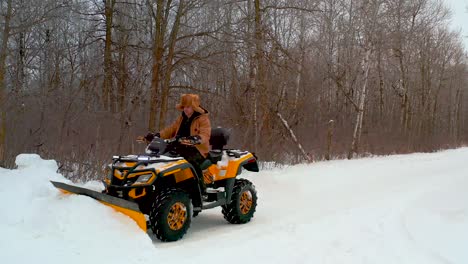 A-man-clears-the-snow-off-his-driveway-with-an-atv-on-a-rural-Canadian-property