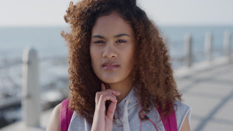 portrait-pensive-young-hispanic-woman-running-hand-through-hair-contemplative-beautiful-female-frizzy-hairstyle-on-seaside-background-slow-motion