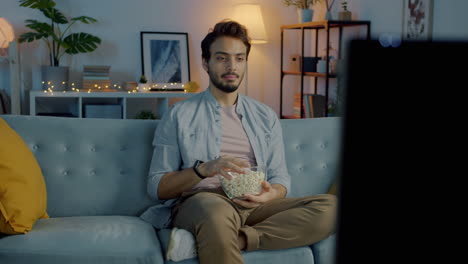 hombre viendo la tv con palomitas de maíz