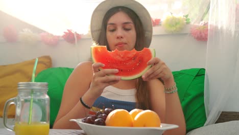 mujer joven comiendo sandía fresca en la tienda del patio trasero