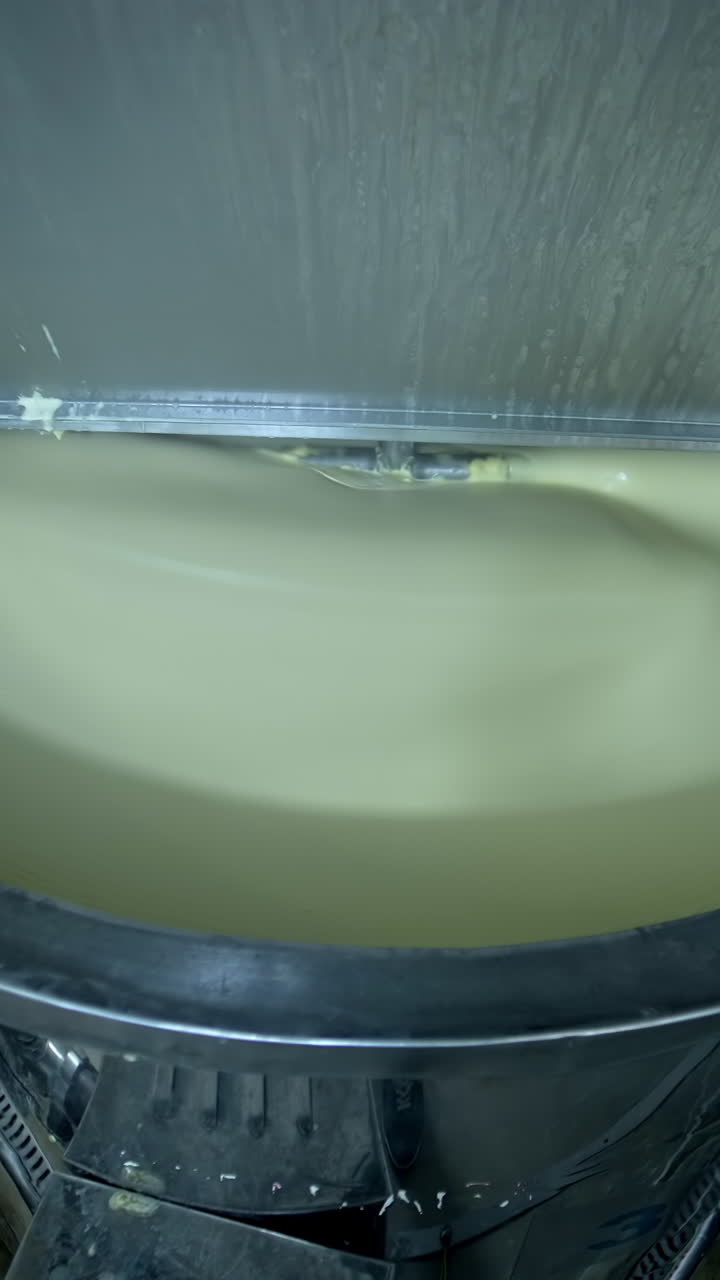 Big cistern with automatic mixing system inside. Beating the butter in automatic mixer tank. Butter production at milk factory close up. Vertical video