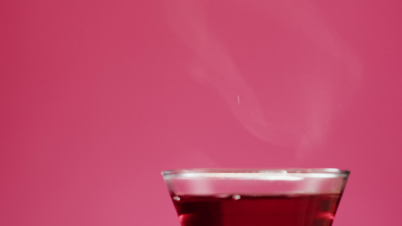 Pouring Hot Red Tea from a Glass Teapot into a Cup