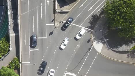 Aerial-rising-above-streets-rounding-bend-at-intersection,-waiting-for-pedestrian