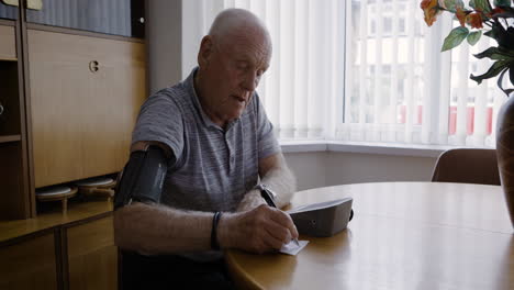 Senior man checking his blood pressure at home
