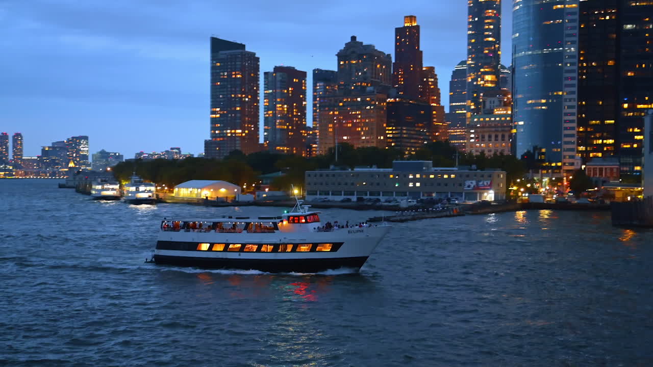 New York, USA, 1 August 2025: Dinner cruise ship sailing near Manhattan skyline at dusk. A dinner cruise ship sails on the Hudson River with illuminated Manhattan skyscrapers in the background