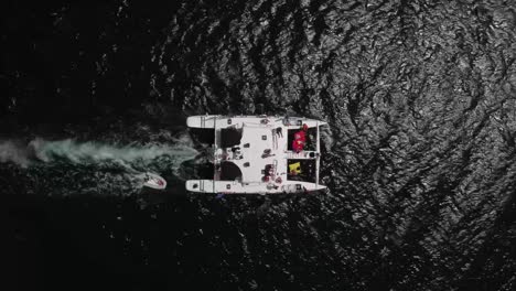 fotografía cenital de un catamarán lleno de turistas, navegando en el mar