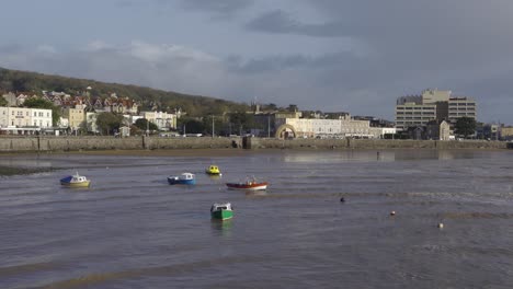 weston super mare, somerset, united kingdom, small fishing boats anchored in yellow sand beach.