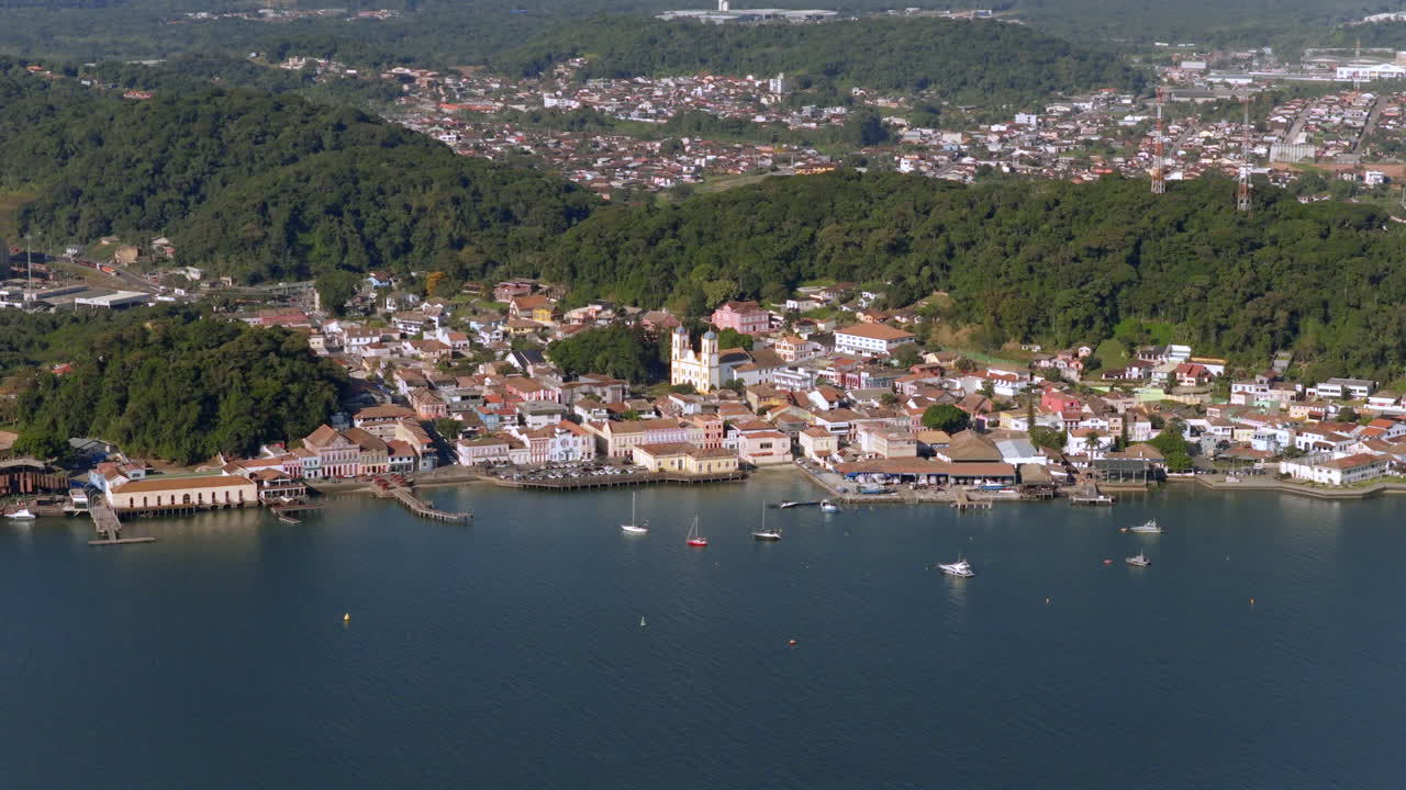 Smooth, lateral drone glide reveals coastal city's layout, architecture, and surrounding natural hills during afternoon