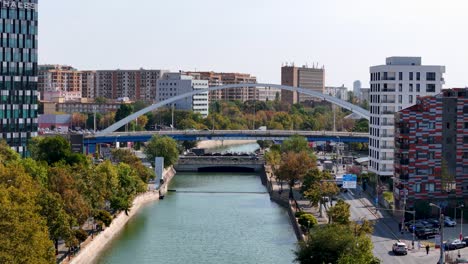 Vista-Aérea-Sobre-El-Río-Dambovita-En-El-Distrito-De-Regie-Con-El-Puente-Grozavesti-Al-Fondo,-Bucarest,-Rumania