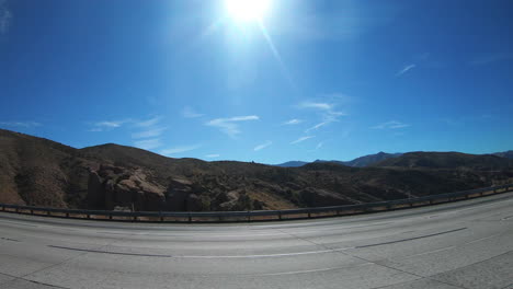 truck traveling in the highways surrounded with the green mountains and cliffs during sunny day - wide shot