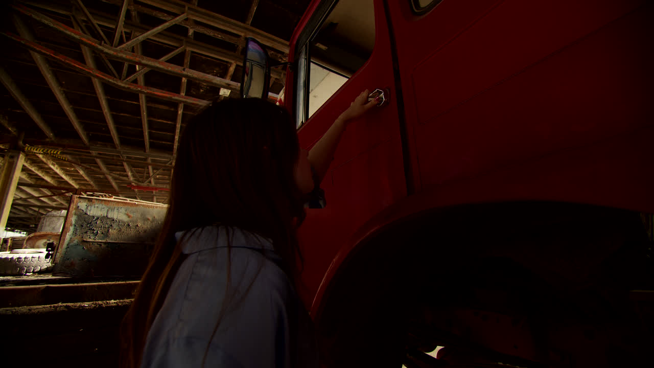 Woman Inspecting a Vintage Red Truck in a Warehouse