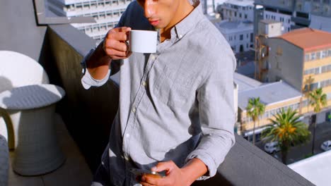 Mann-Benutzt-Handy,-Während-Er-Auf-Dem-Balkon-Kaffee-Trinkt-4k