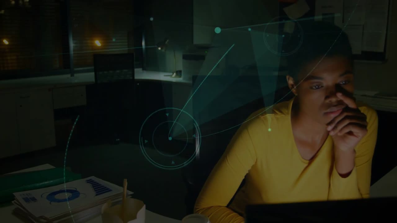 Woman working late, sipping coffee then leaning into laptop, initiating animated graphs for finance