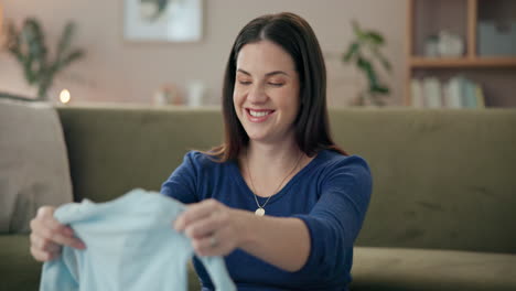 pregnant woman holding baby clothes