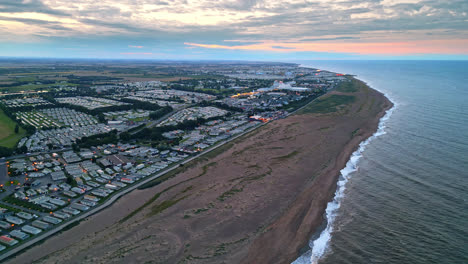 Skegness-seaside-town-seen-from-aerial-drone-at-sunset:-holiday-park,-beach,-caravans,-and-sea