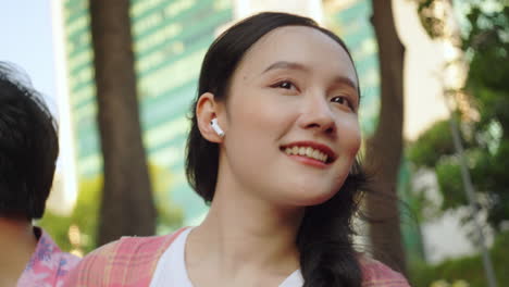 asiatic woman portrait close up while travelling on big city skyline listening to music and smiling