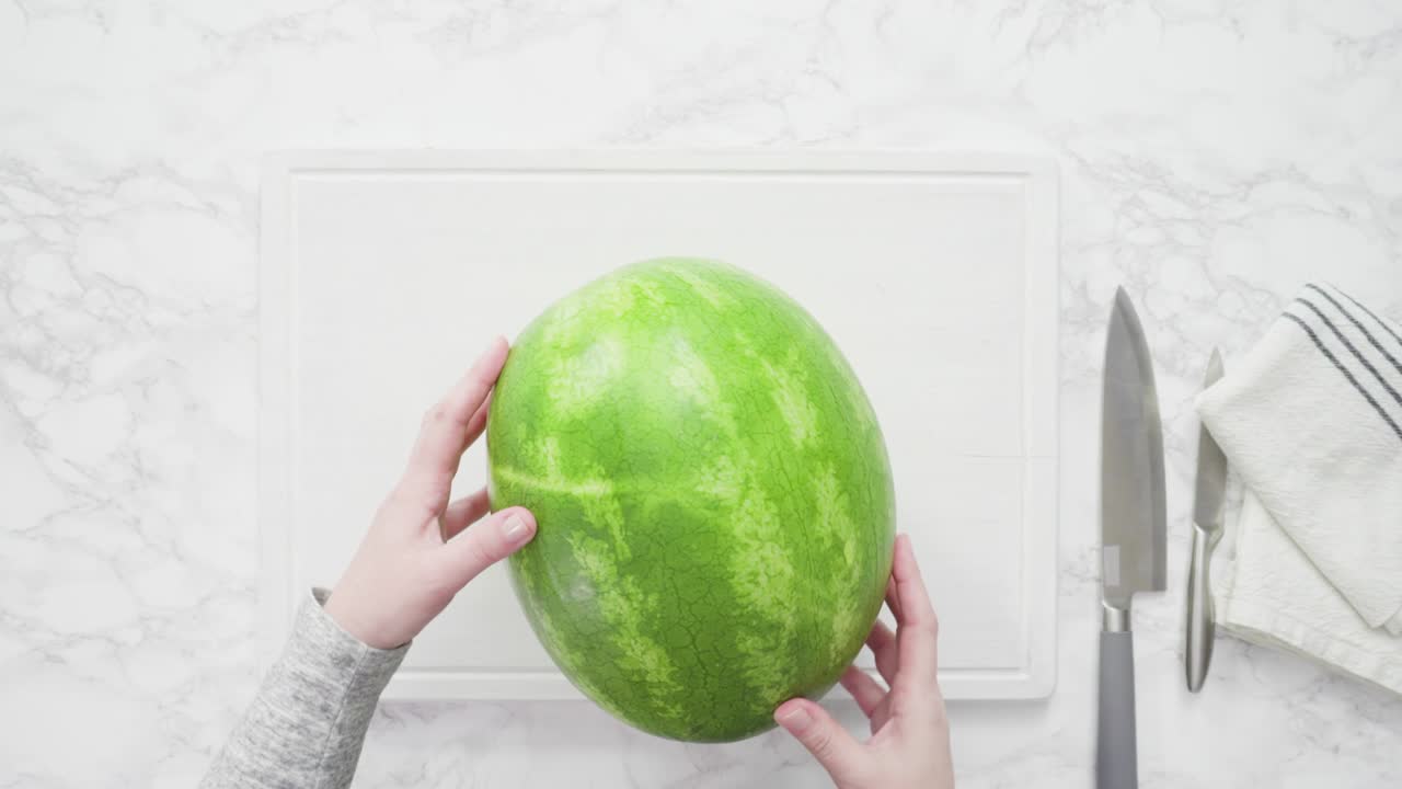 sandía roja sin semillas en una tabla de cortar blanca.