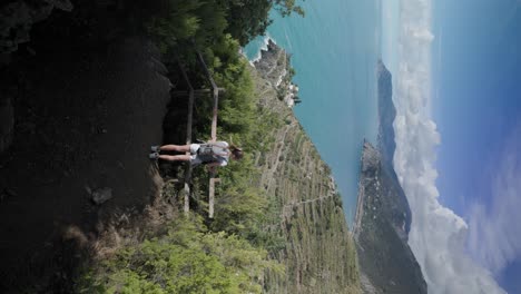 vertical shot of a female traveler with backpack hiking on the amalfi coast in summer in italy