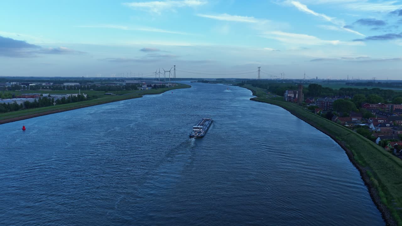 Backward panoramic drone movement behind the Vincitus Dordrecht cargo vessel moving through Oude Maas distributary, Zuid-Holland, Netherlands