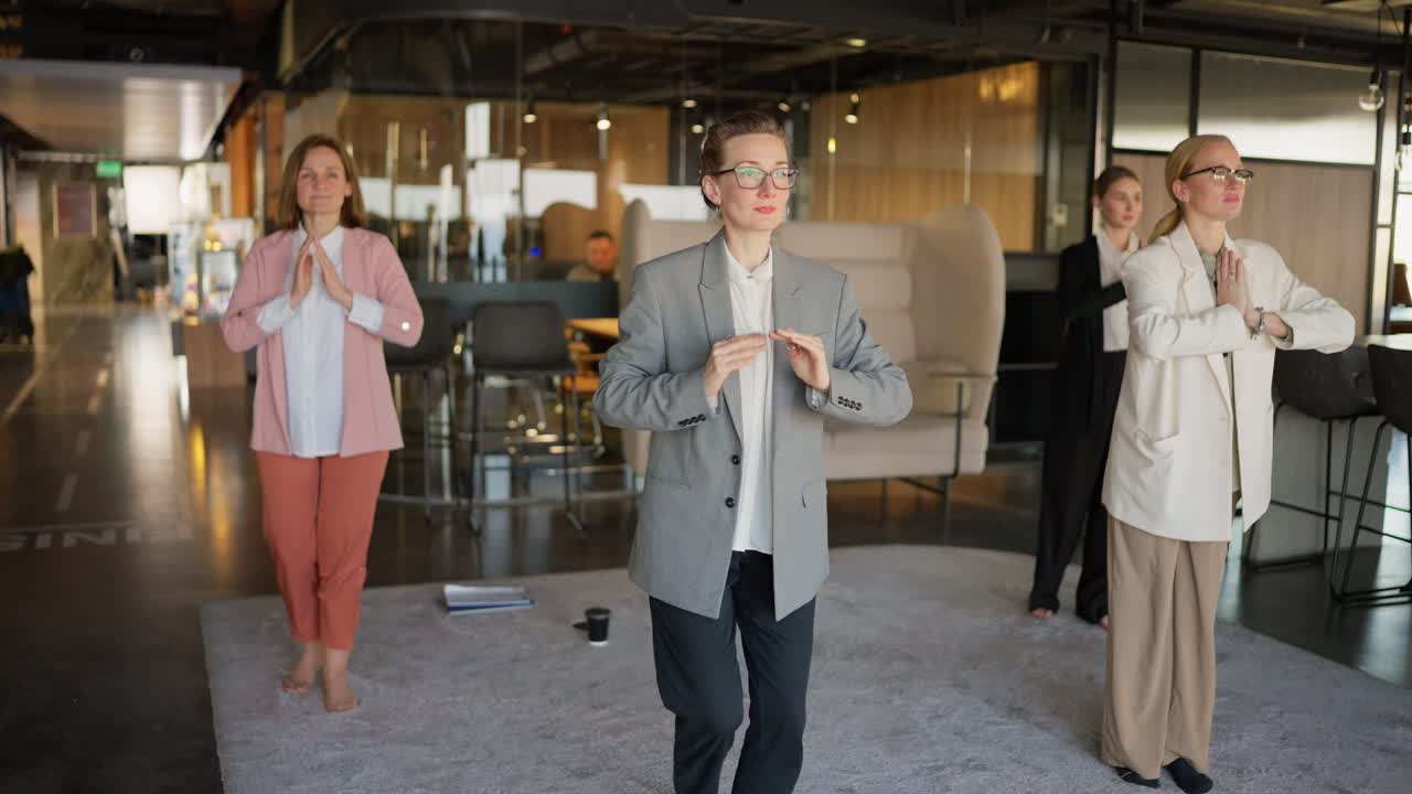 직장에서 휴식을 취하는 동안 현대적인 사무실에서 회색 부드러운 카에서 요가를하는 비즈니스 슈트를 입은 자신감있는 비즈니스 여성 그룹 요가 수업과 사무실에서 일하는 동안 영적 지원