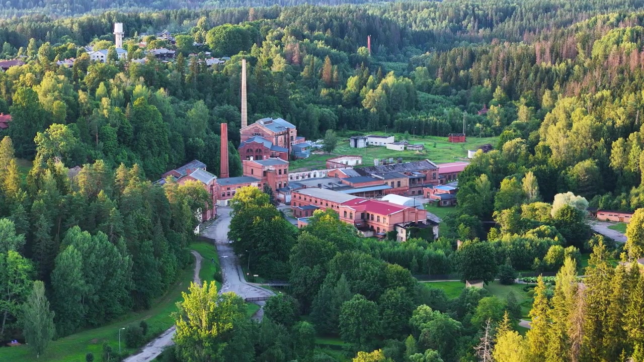 Storica cartiera di Ligatne, che mostra il patrimonio industriale culturale della Lettonia, circondata dalla foresta, ripresa aerea con drone che si sposta a sinistra per inquadrare
