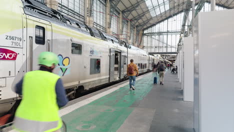 people walk by sncf train at gare d’austerlitz station in paris, france
