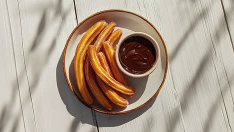 delicious churros with chocolate sauce on rustic plate