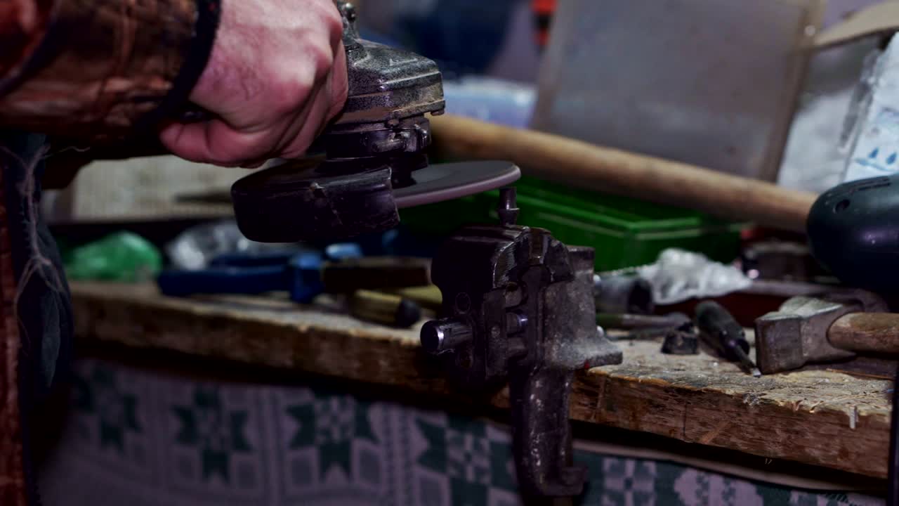 el trabajador mola el producto metálico con un primer plano de una máquina de molienda