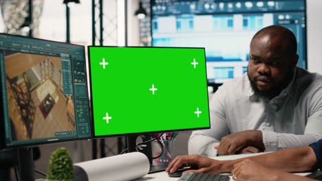 man working in office with green screen monitor