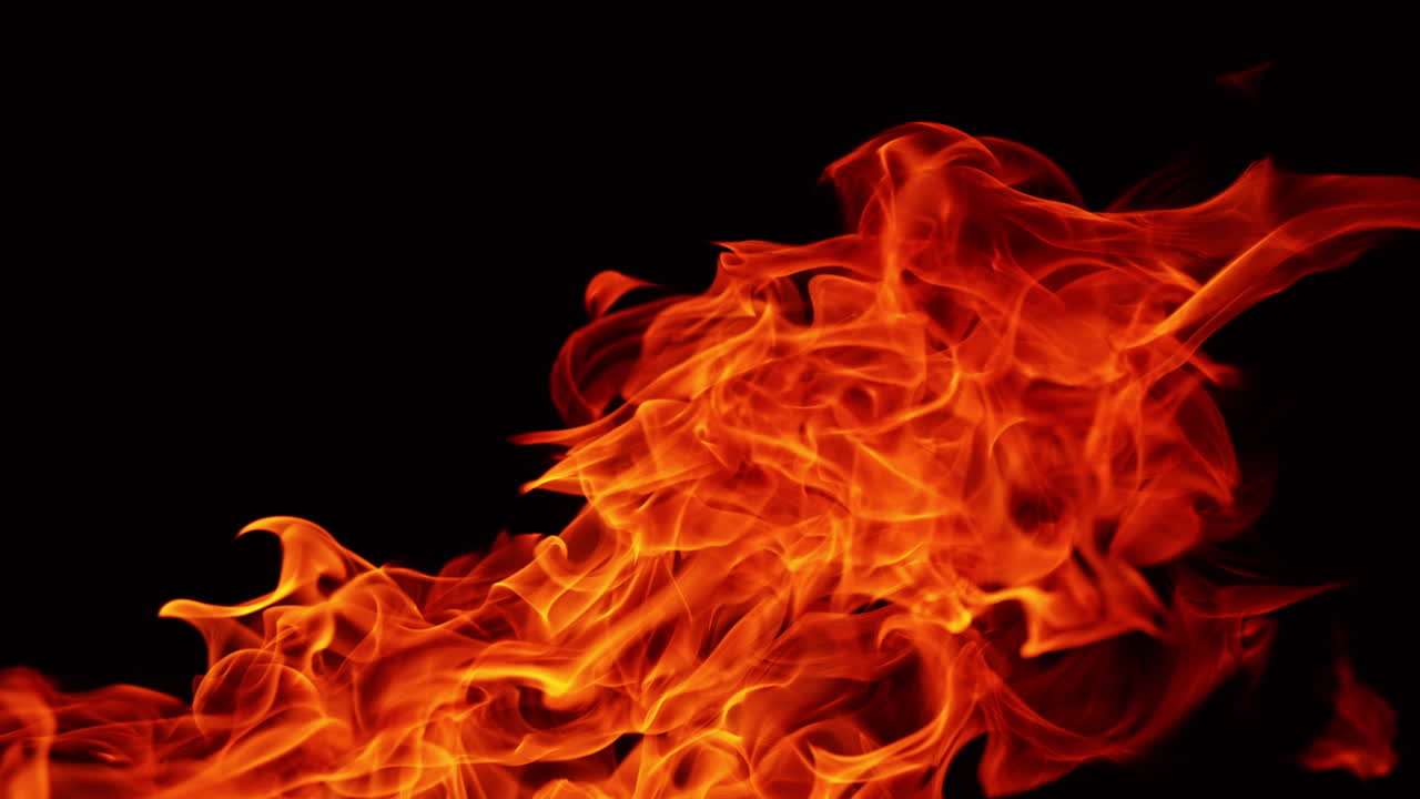 Big long tongues of flame moving to the right. Fire burning at night. Close up.