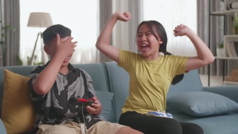 asian children with joystick game play video game on tv, girl celebrating victory and boy disappointed