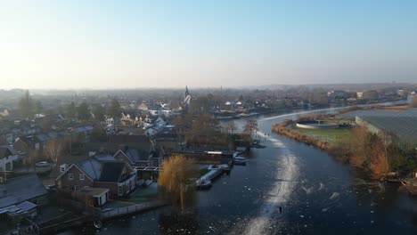 aerial ascending view of locals ice skating over frozen canals in hendrik-ido-ambacht