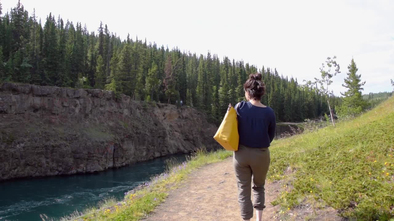 Indian woman walks along the Yukon River, long shot