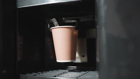 coffee machine dispensing paper cup, automated drink preparation, beverage service, coffee shop machine close-up, paper cup placement, cup dispenser mechanism, hot drink preparation