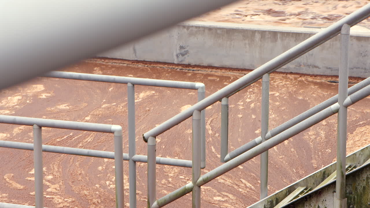 Water froths and flows vigorously through aeration baths at a wastewater treatment plant, moving from one channel to another in a dynamic, industrial process