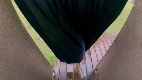 view through parted dark curtain catching wind revealing a rain-soaked wooden deck floor framed by brown curved walls. shot in the baltics