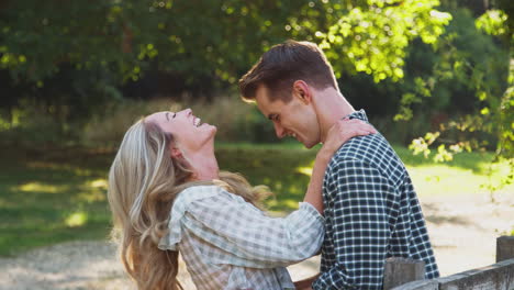 Loving-Young-Couple-Meeting-By-Fence-On-Walk-In-Countryside-Together-And-Hugging