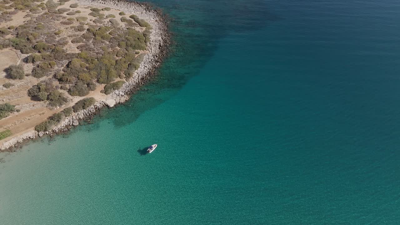 Aerial - small boat anchored in turquoise waters near Voulisma Beach in Crete Greece