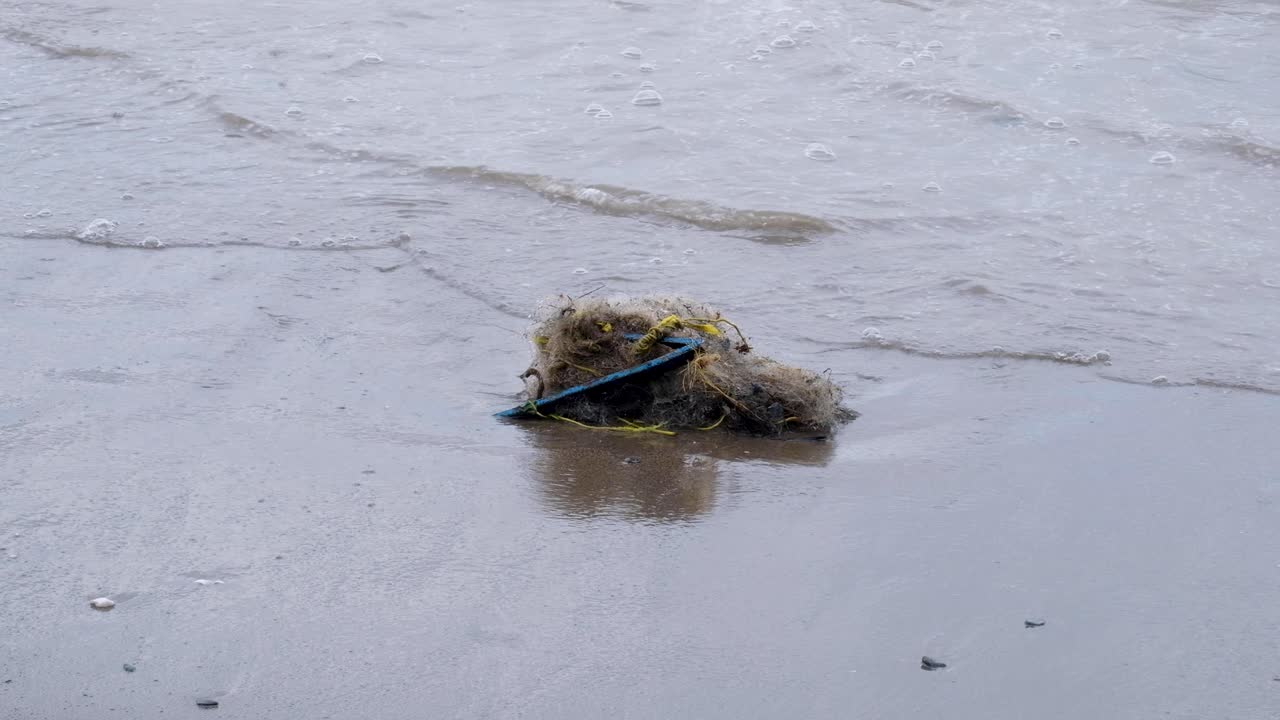 A pile of tangled and damaged fishing nets and other trash washed onto beach of a remote tropical island