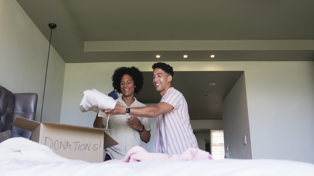 African American men using phone sorting items packing pillow into DONATIONS in bedroom taking pic