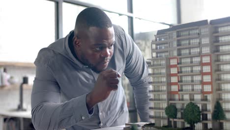 focused african american casual businessman inspecting city model in office in slow motion