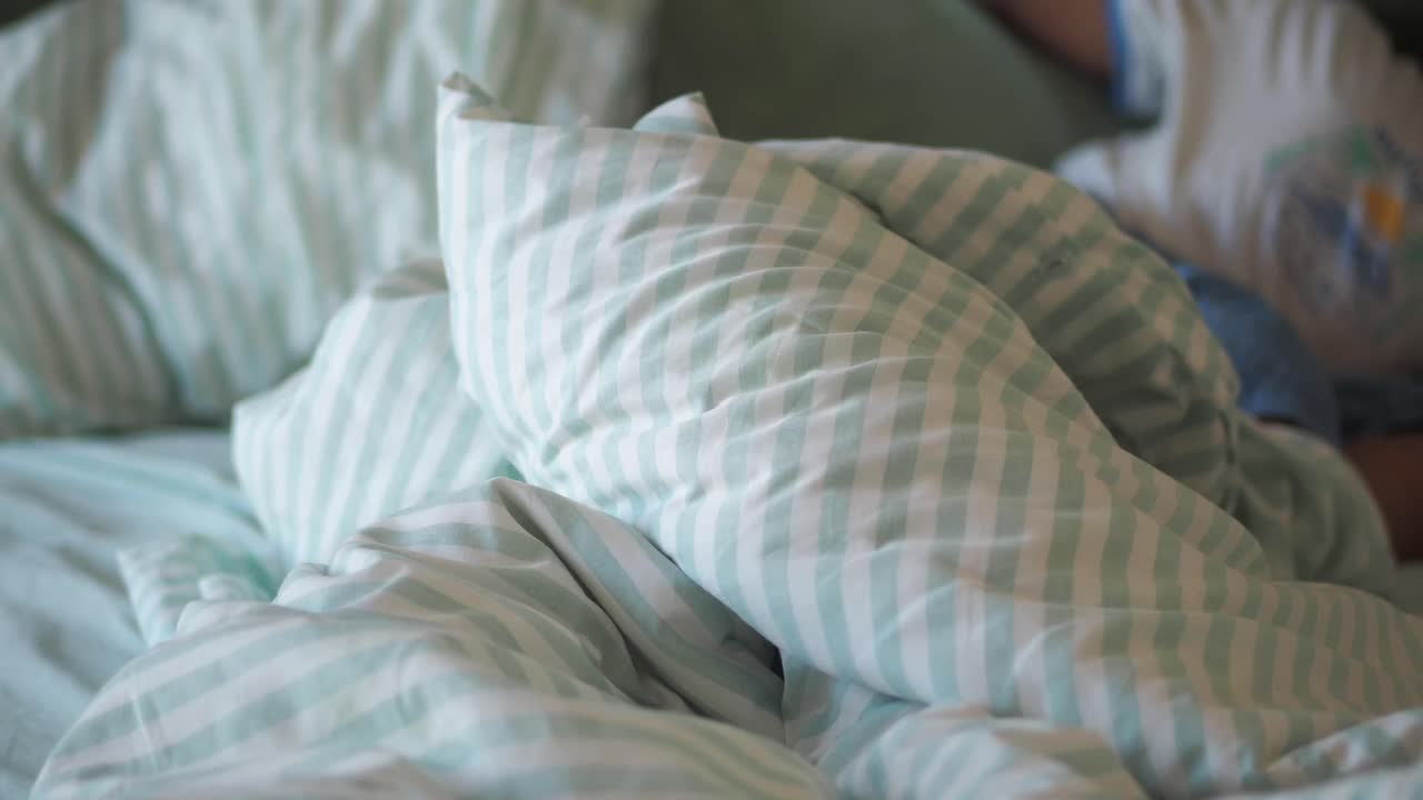Cama deshecha con almohadas a rayas y edredón