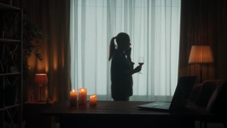 woman relaxing with wine by the window at night